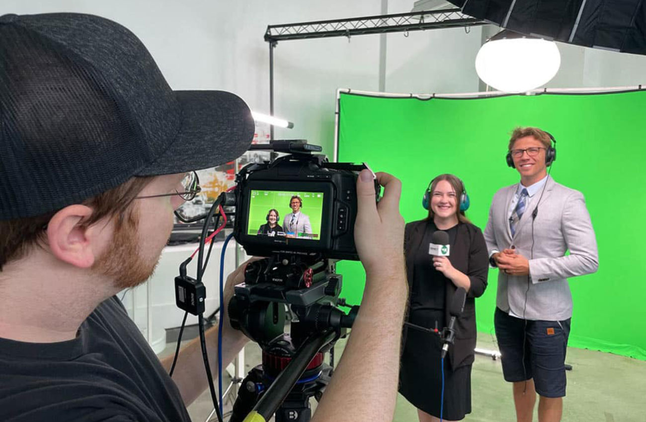 Three YLB team members filming Acuity Brands's racing-themed Connect Sales conference video against a green screen.