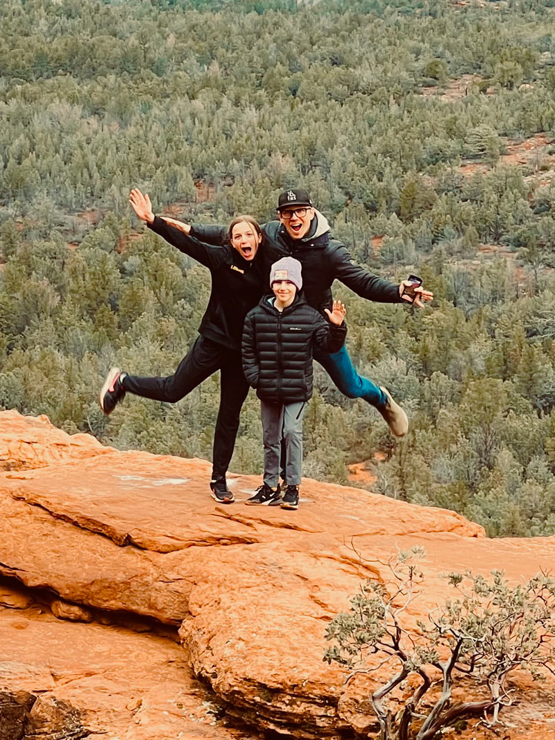 A photo of Jonathan and his family standing on a scenic cliff
