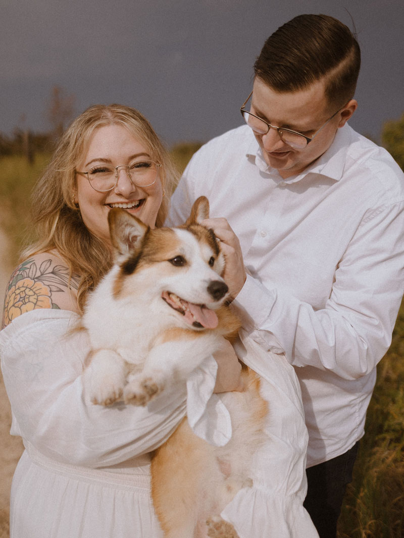 A photo of Sydney, her partner, and their corgi.